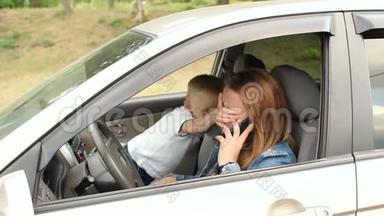 淘气的孩子在车里干扰妈妈，他用手闭上她的眼睛。